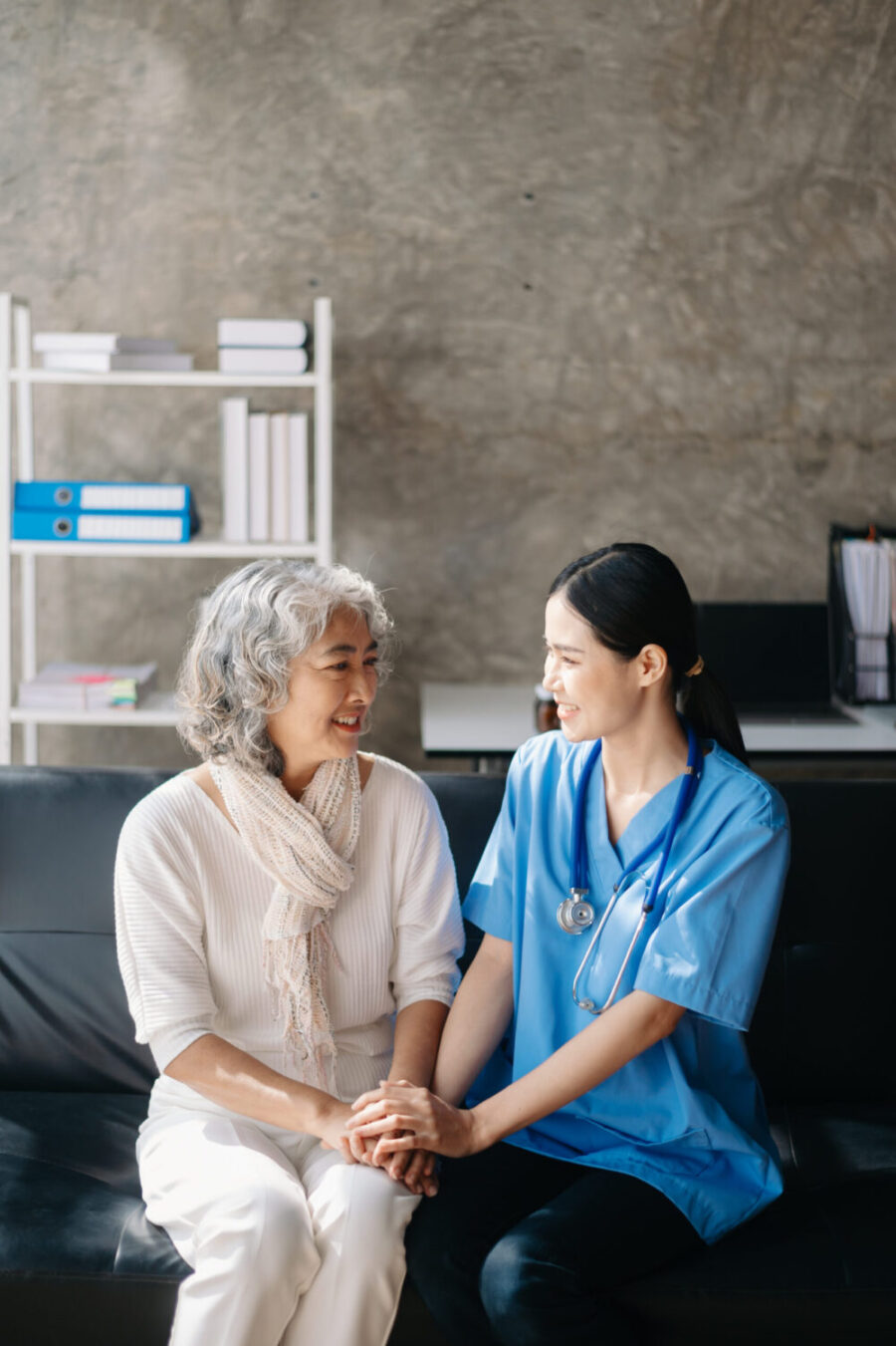 Asian caregiver doctor examine older patient woman therapist nurse at nursing home taking care of senior elderly woman sit on sofa.Medical service concept. to help and encourage.
