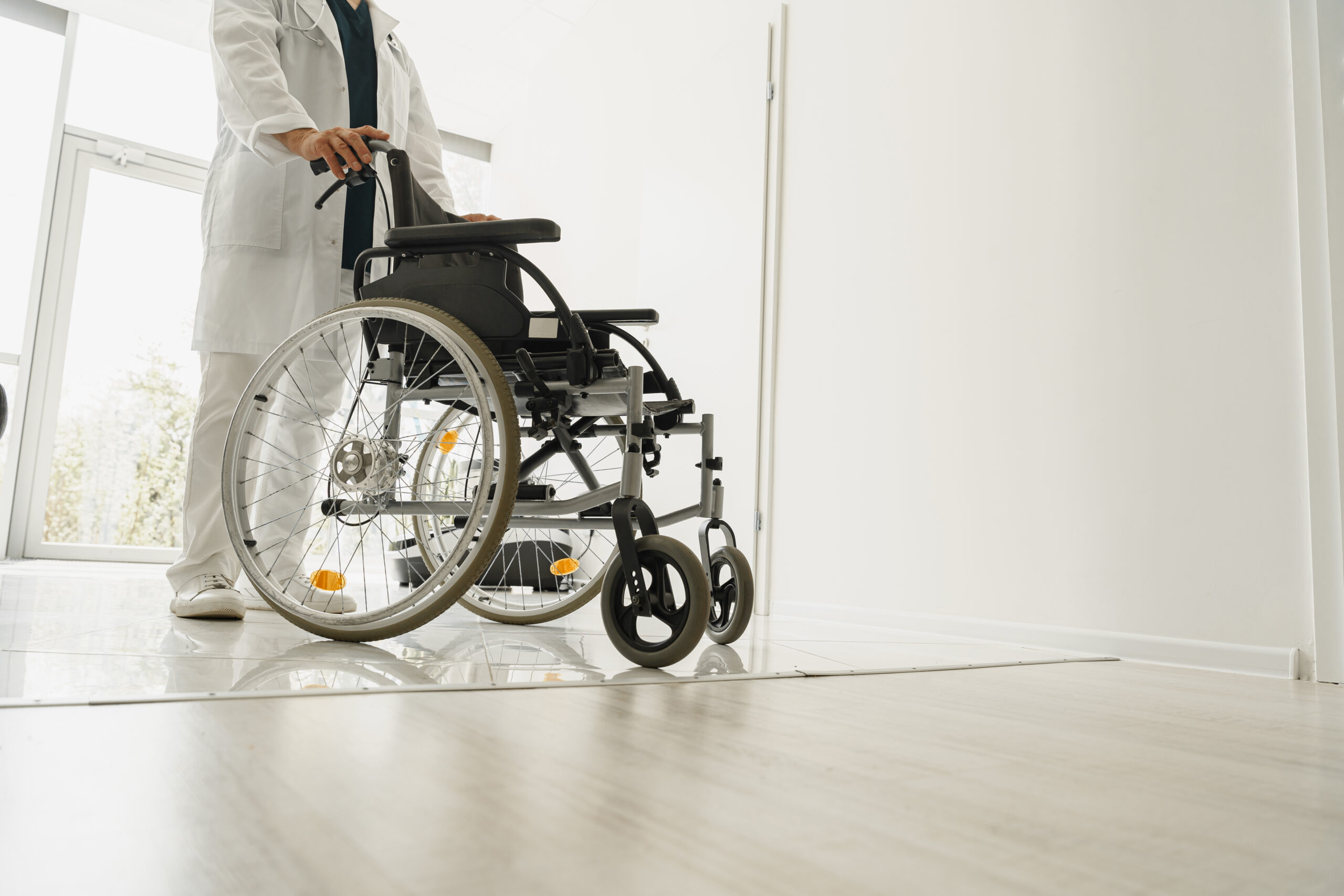 Closup of professional male doctor holding wheelchair in hospital clinic hall. High quality photo