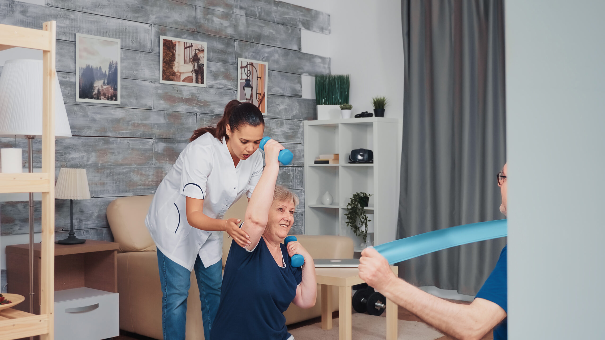 Senior couple exercising with therapist on yoga mat at home. Home assistance, physiotherapy, healthy lifestyle for old person, training and healthy lifestyle
